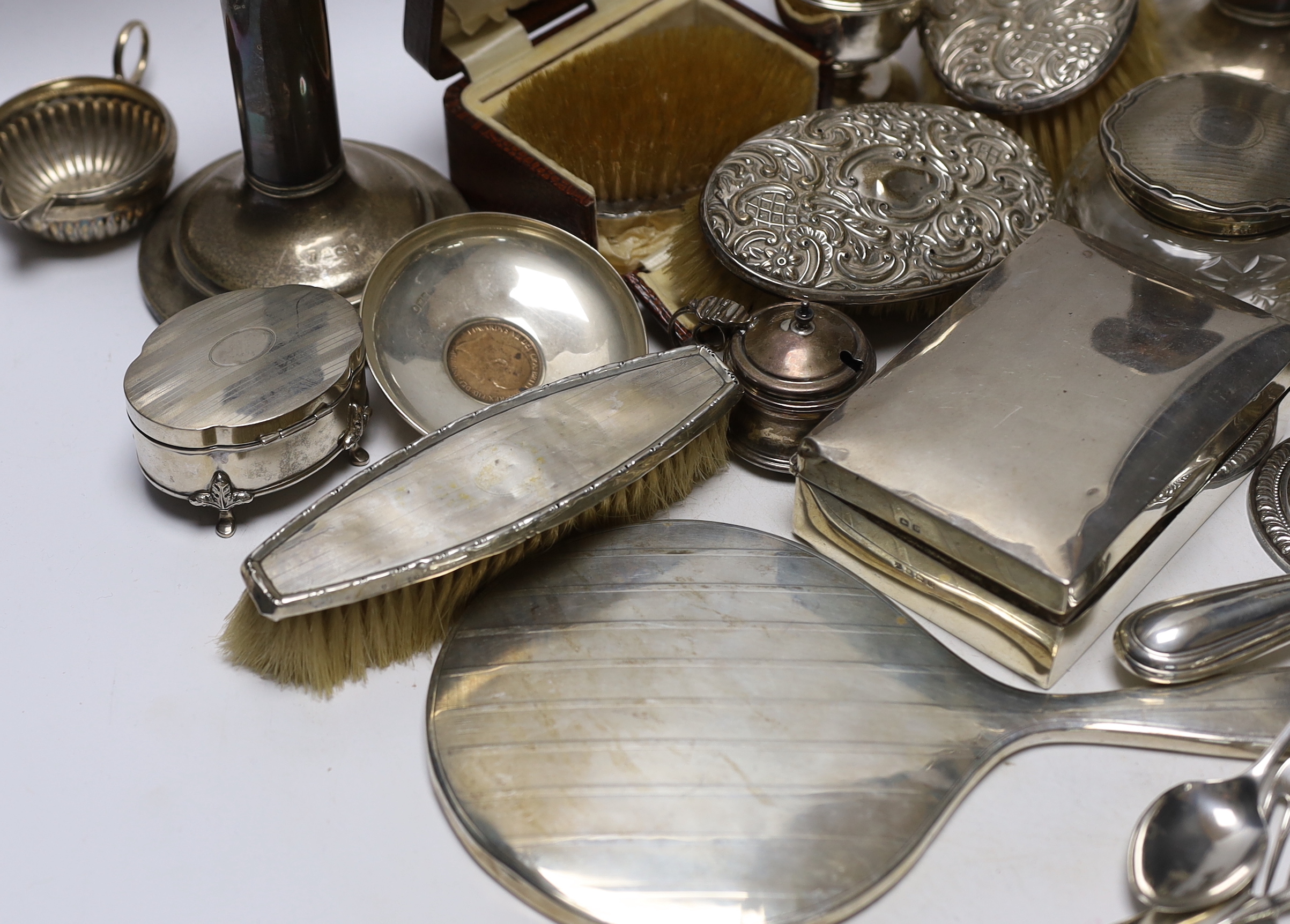 Sundry silver items including a pair of candlesticks, marks rubbed, handled magnifying glass, lidded vase, hand mirror, five brushes, cigarette box, trinket box, toilet jar and eleven other items including a novelty shoe